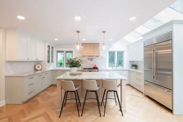 Beachwood, OH kitchen remodel with white cabinets, island seating, built-in stainless refrigerator and herringbone wood floor