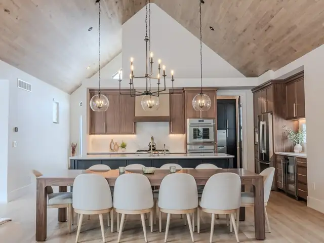 Award-winning custom home by Keselman Construction Group with a vaulted wood ceiling, a chandelier over the dining table and wood kitchen cabinets