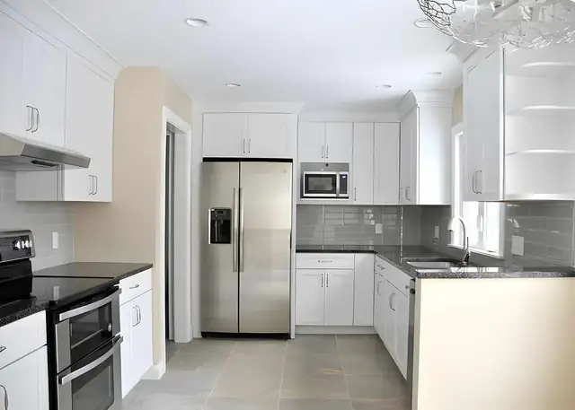 Kitchen restored by Keselman Construction Group after fire damage, with white shaker cabinets, a gray tile backsplash and stainless appliances