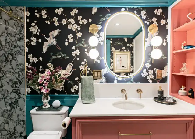 Solon, OH powder bath remodel with crane-print wallpaper, coral vanity with open shelves, oval lighted mirror and brass faucet