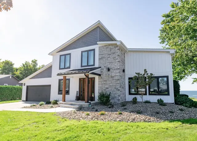 Front of the Eastlake, OH home remodeled by Keselman Construction Group with gray siding, a stone column and a covered entry