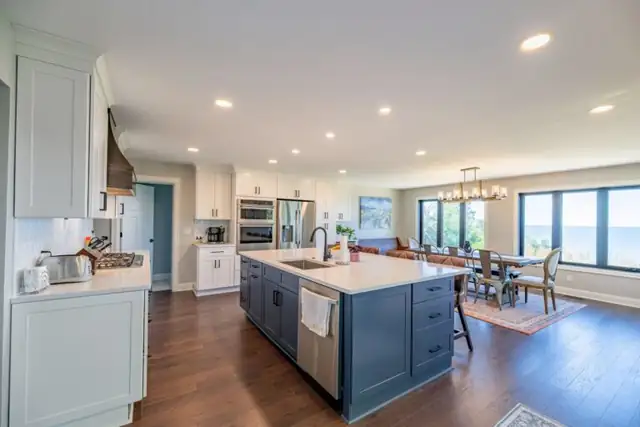 Eastlake, OH home remodel with open kitchen, navy island, hardwood floors and dining area by the windows