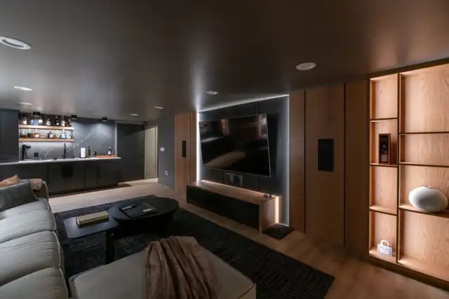 Pepper Pike, OH basement remodel with dark media wall, backlit TV, lighted oak shelving and sectional sofa